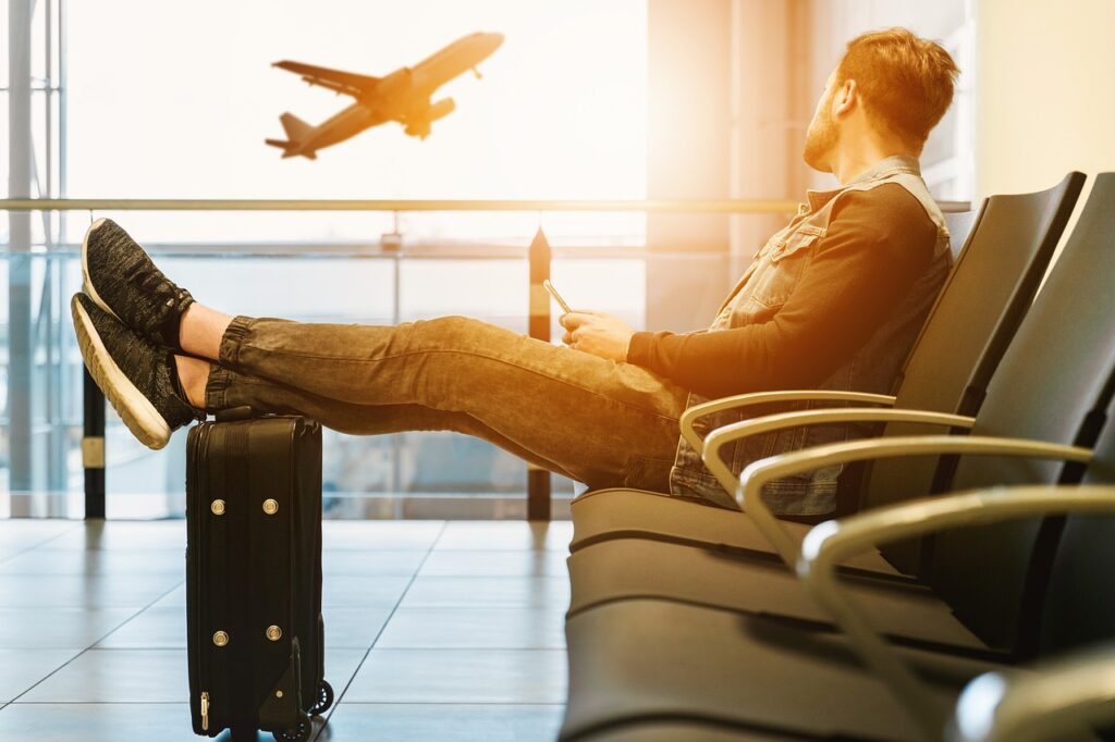 A man sitting in a chair looking at a plane taking off after spending the night at one of the Columbia, SC airport hotels.