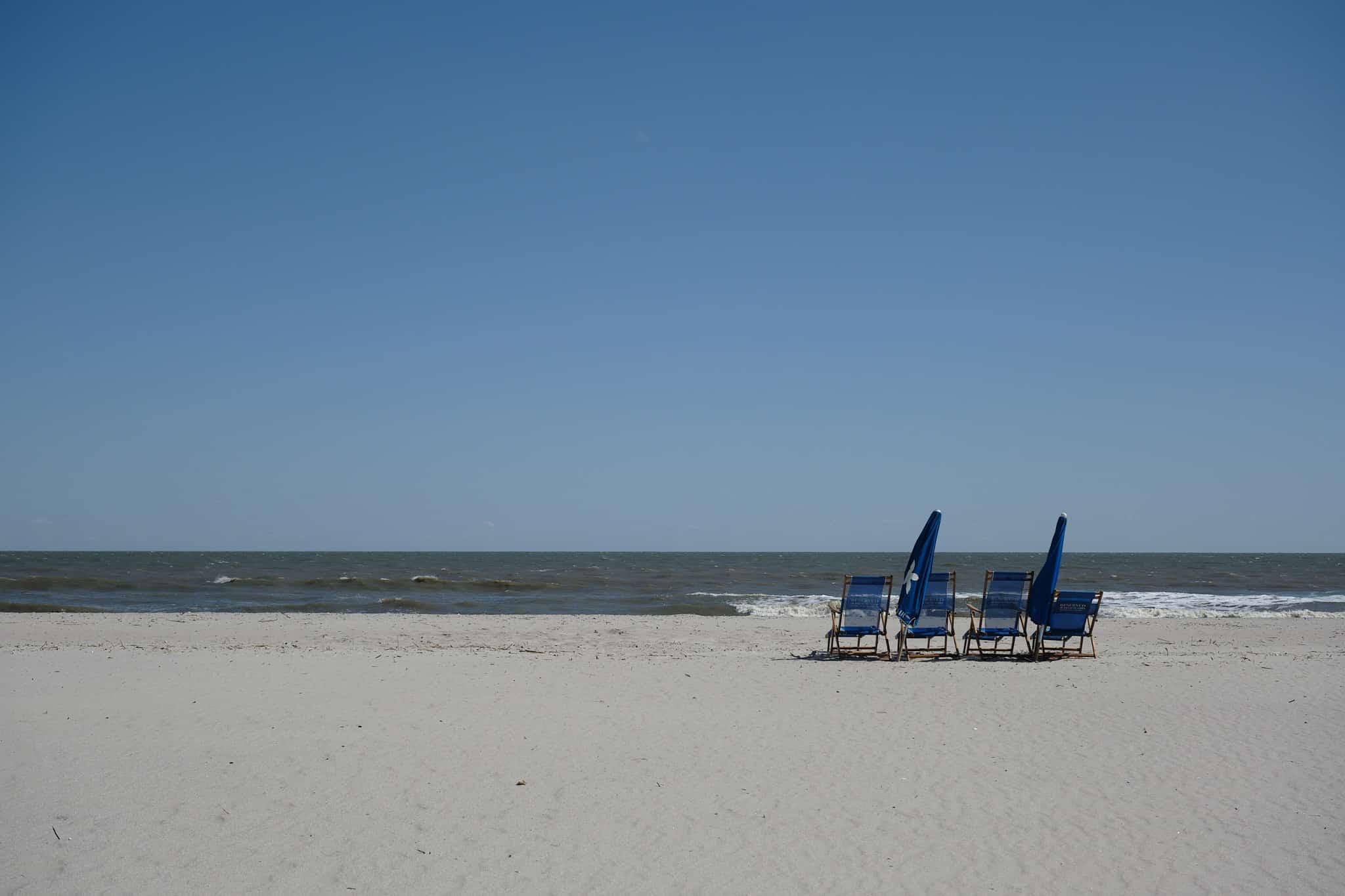 Photo of 4 chairs on a Charleston beach overlooking the ocean.