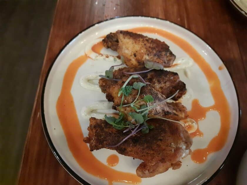 Photo of chicken wings on a plate with some sauces.