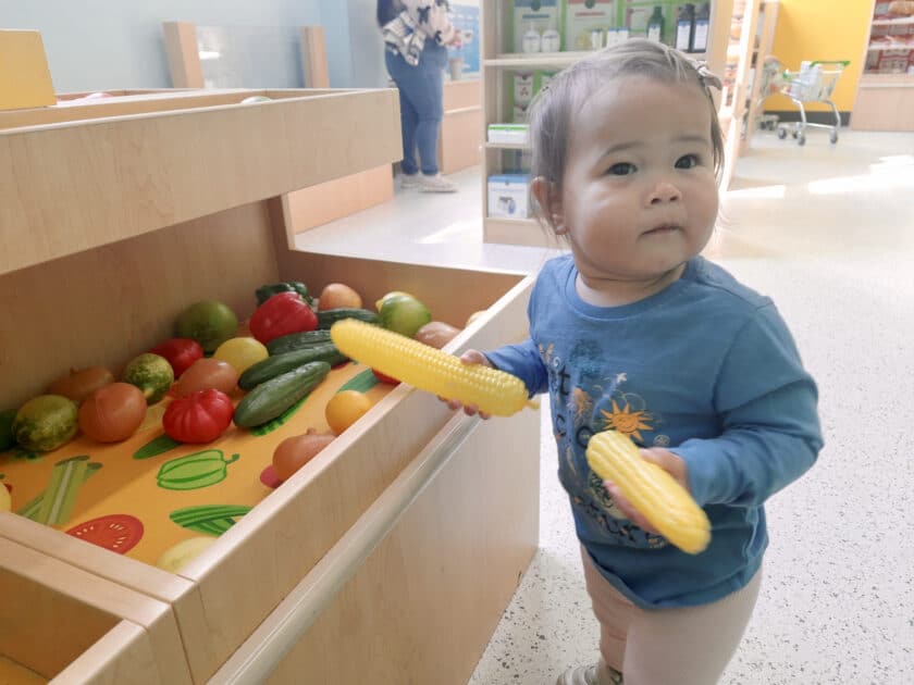 Child holding plastic corn at the Columbia Childrens Museum EdVenture