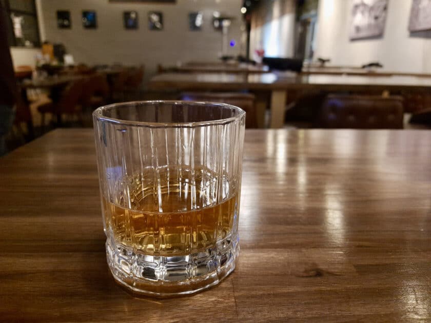 A glass of whiskey on a table at the Columbia Steel Hands Vista location.