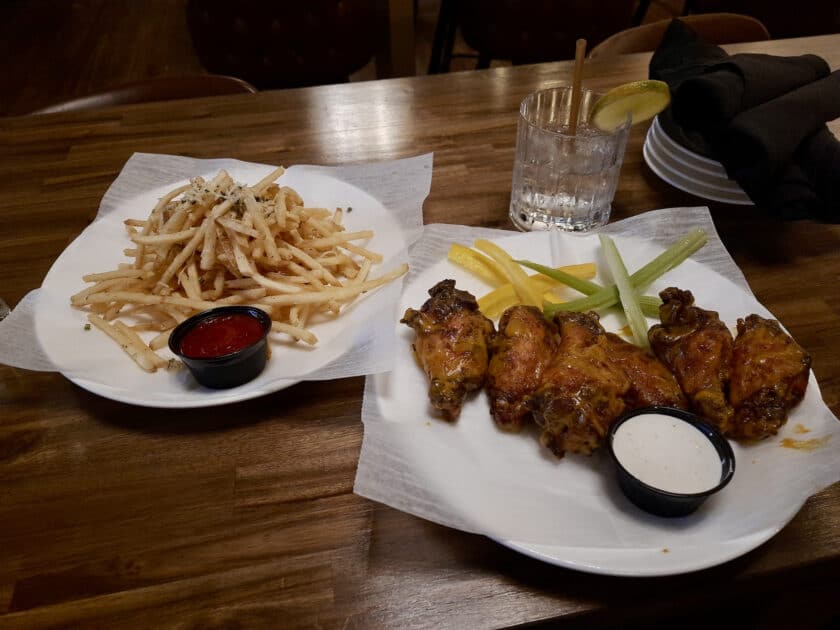 A plate with chicken wings and one with french fries at the Steel Hands Distillery in the Vista.