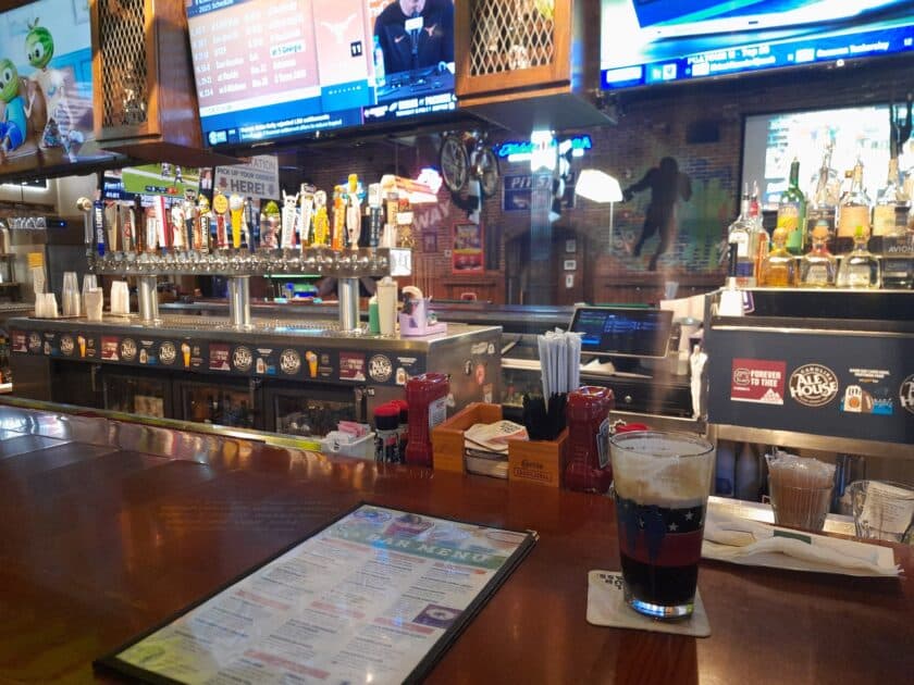A Carolina Ale House menu on the bar next to a beer.