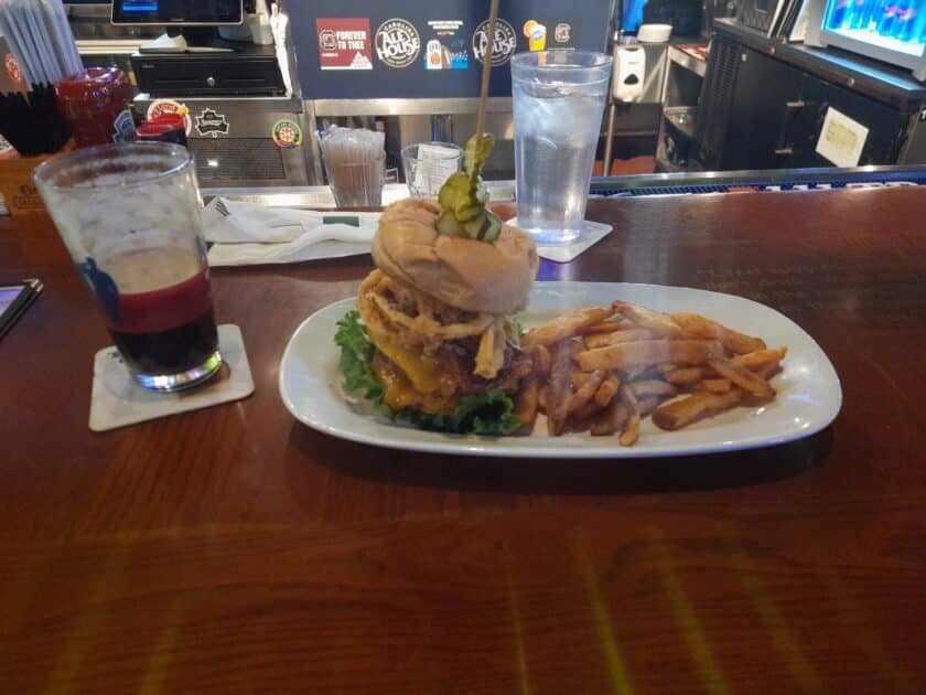 A hamburger and fries on the bar with a beer next to it at Carolina Ale House in Harbison, SC.