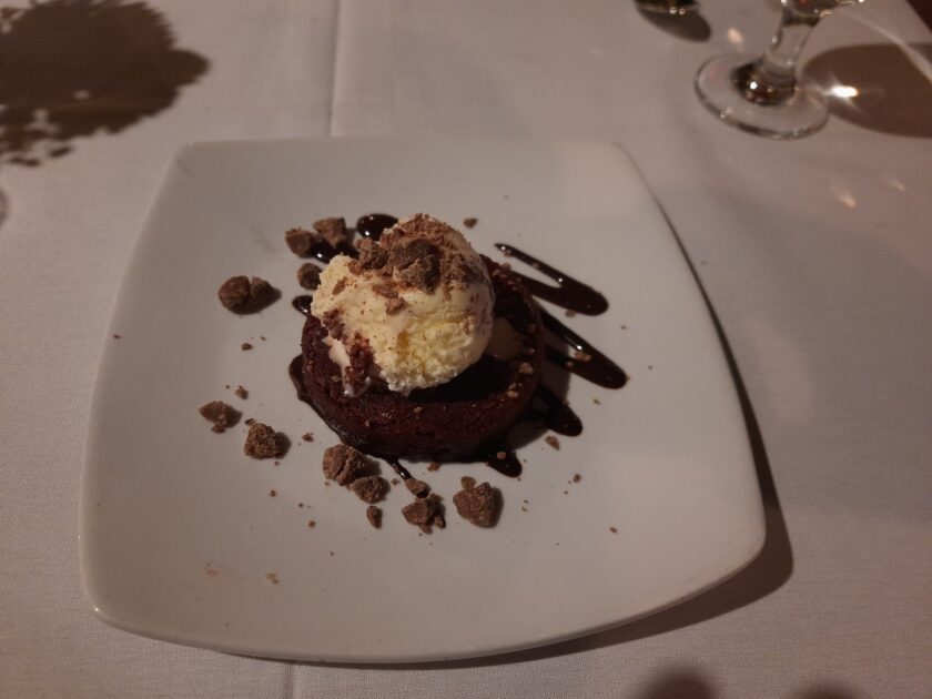 A plate with a brownie with ice cream on top with bits of chocolate at Saluda's Restaurant.