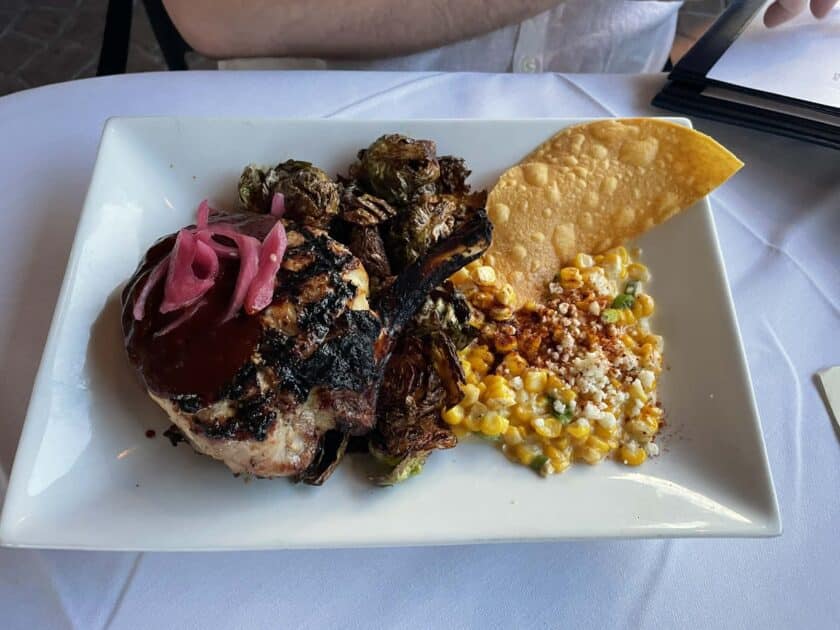Photo of a plate with a pork chop, brussels sprouts and corn at Saluda's in Columbia, SC.