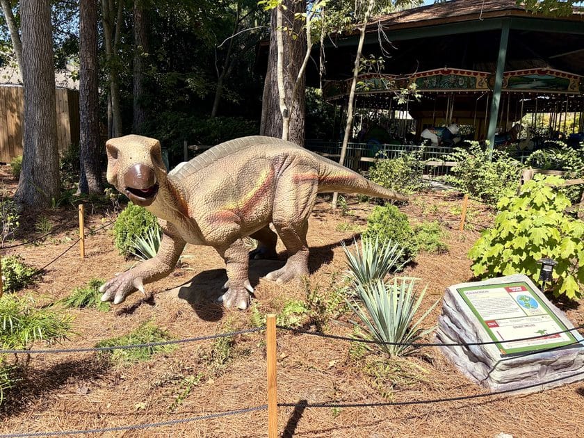 A small dinosaur at Riverbanks Zoo with a sign to the right.