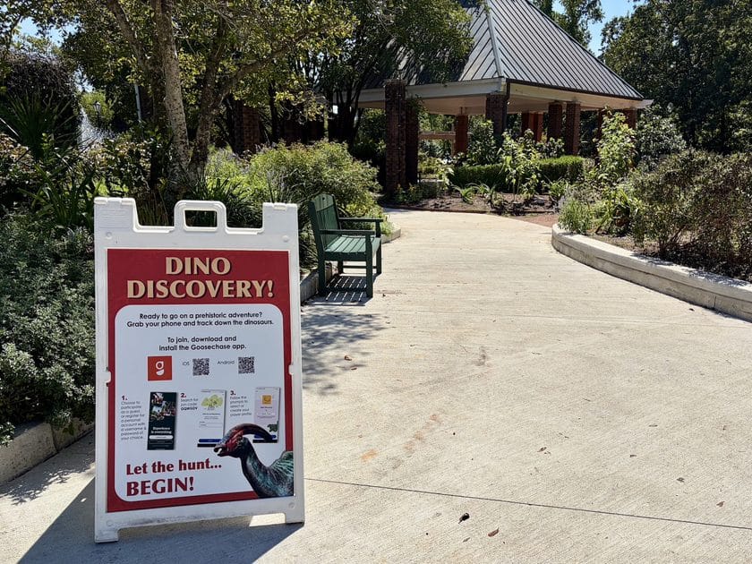 Sidewalk with a sign for the scavenger hunt for dinosaurs at Riverbanks Zoo in Columbia, SC.